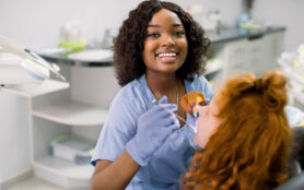 Smiling,Black,Woman,Dentist,Wearing,Blue,Uniform,,Providing,Tooth,Restoration