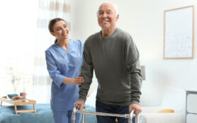 Care,Worker,Helping,Elderly,Man,With,Walker,In,Geriatric,Hospice