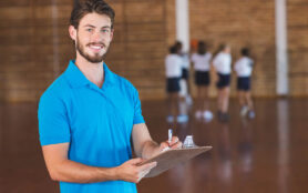 Portrait,Of,Sports,Teacher,Writing,On,Clipboard,In,Basketball,Court