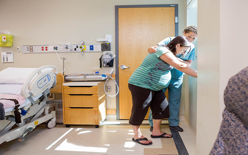 Mid,Adult,Female,Nurse,Comforting,Tensed,Pregnant,Woman,Leaning,On