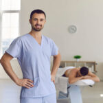 Young,Smiling,Confident,Man,Professional,Chiropractor,Masseur,Standing,And,Looking