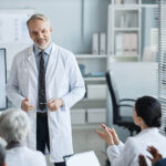 Happy,Experienced,Clinician,In,Lab,Coat,Standing,In,Front,Of