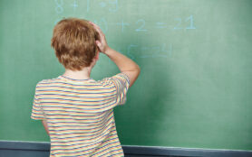 Child,Standing,In,Class,In,Front,Of,Chalkboard,And,Thinking