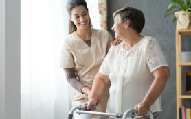 Smiling,Nurse,Helping,Senior,Lady,To,Walk,Around,The,Nursing