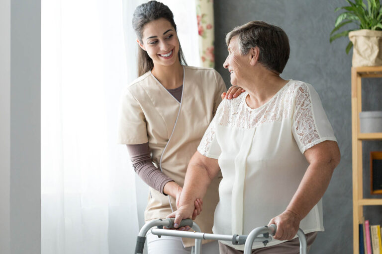 Smiling,Nurse,Helping,Senior,Lady,To,Walk,Around,The,Nursing