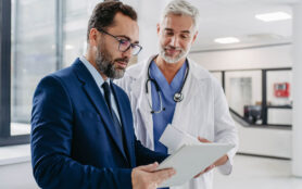 Pharmaceutical,Sales,Representative,Talking,With,Doctor,In,Medical,Building,,Presenting